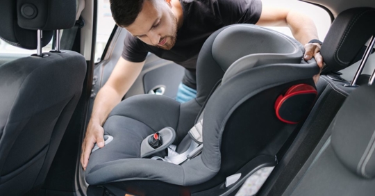 Dad installing car seat in car