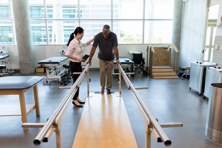 man in physical therapy learning to walk again