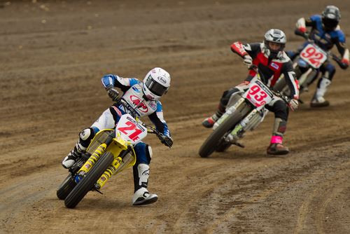 Photo of three dirt bike racers turning a corner of a track during a race